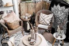 a black and white boho balcony with wicker chairs, a Moroccan pouf, a small side table, baskets and candle lanterns and beautiful Morocco-inspired blankets, pillows and rugs