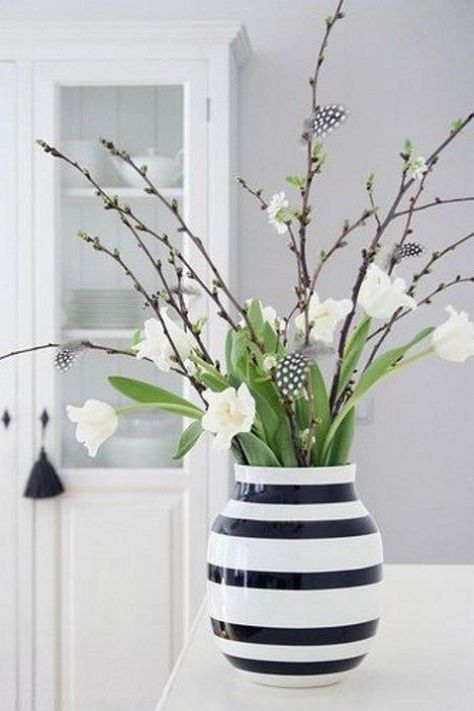 a black and white vase with white tulips, willow and little feathers is a gorgeous modern Easter centerpiece