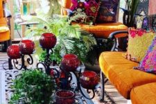 a boho Asian porch with dark furniture, bright upholstery and textiles, a carved table and red candle holders