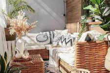 a boho balcony done in black and white, with wicker furniture, potted plants, candle lanterns and lights and black and white upholstery
