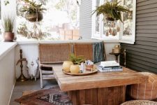 a boho porch with wooven and woven furniture, boho layered rugs, potted greenery and brass touches