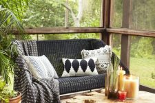 a boho screened porch with woven and wooden furniture, printed textiles, a wood slice rug and potted greenery