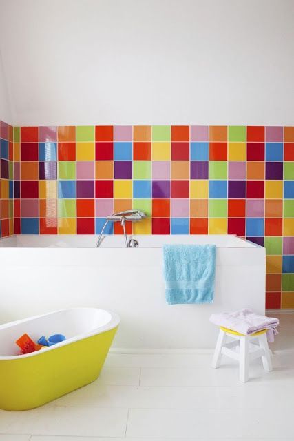 a bright and inspiring bathroom in white but with super bold tiles for an accent, with a small colorful tub and bright textiles is ultimate
