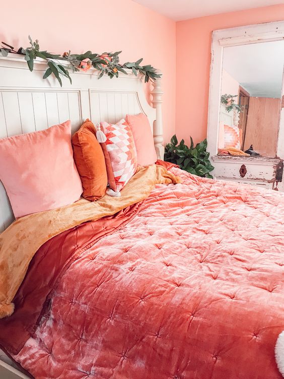 a bright spring bedroom with coral and pink bedding, faux greenery and blooms