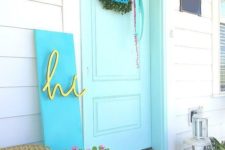 a bright spring porch with a floral mat, potted blooms, a greenery wreath, a modern colorful sign
