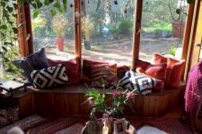 a colorful boho screened porch with a built-in bench, super bright textiles, faux fur, greenery and a Moroccan lantern