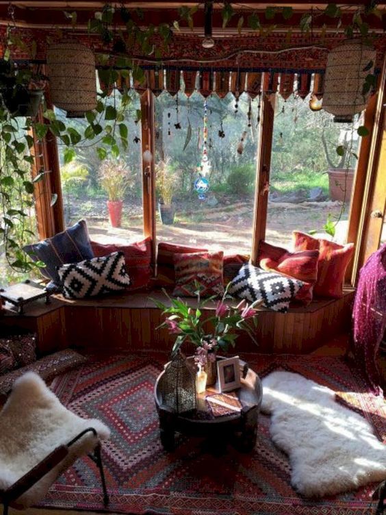 a colorful boho screened porch with a built in bench, super bright textiles, faux fur, greenery and a Moroccan lantern