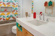 a contemporary bathroom done with much concrete and stone, with a colorful tile accent wall and matching colorful touches