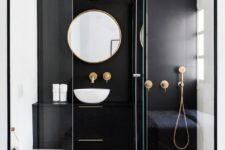 a contrasting small bathroom with a black statement wall and vanity, a shower, a round mirror and a bowl