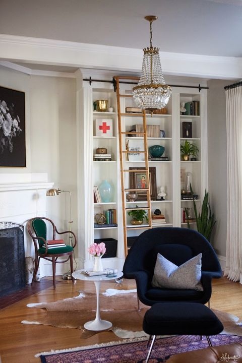 a cozy and stylish reading nook with built-in bookshelves, a navy chair with a footrest and a refined chair