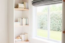 a cozy windowseat with built-in bookshelves on both sides and a grey curtain is a stylish space