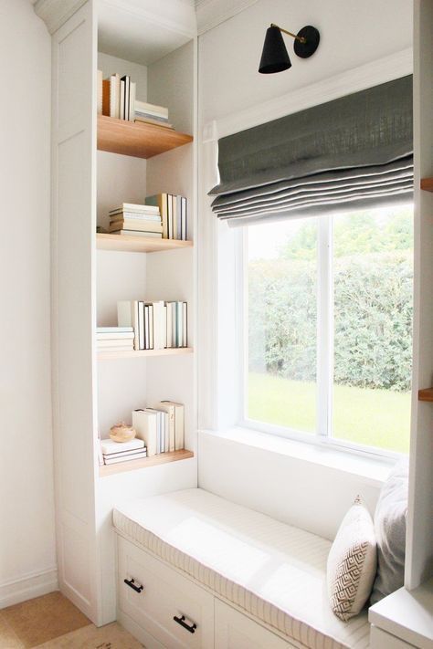 a cozy windowseat with built-in bookshelves on both sides and a grey curtain is a stylish space