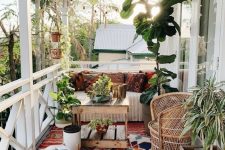 a lovely boho porch with wooden and woven furniture, colorful printed textiles, potted plants and greenery, layered rugs