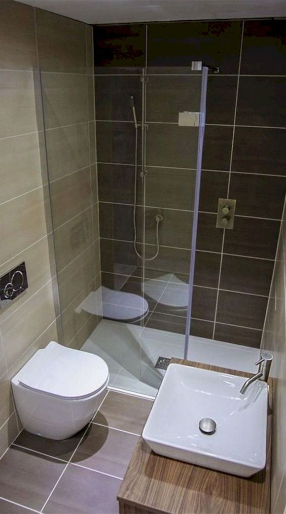 a minimalist bathroom done with earthy and sandy tiles, a wooden vanity with a square sink and a shower space