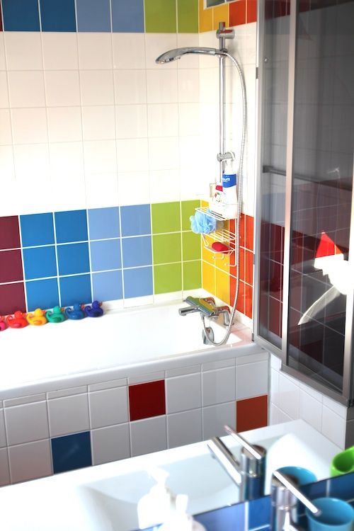 a modern bathroom accented with super bright tiles in all the colors of the rainbow and small ducks repeating these colors