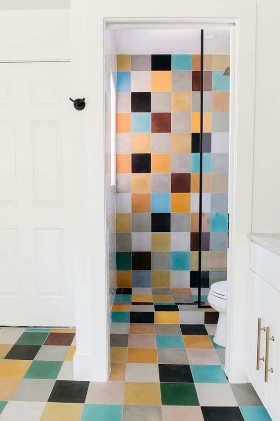 a modern bathroom clad with colorful tiles, with white appliances and a vanity that balance out the bold tiles