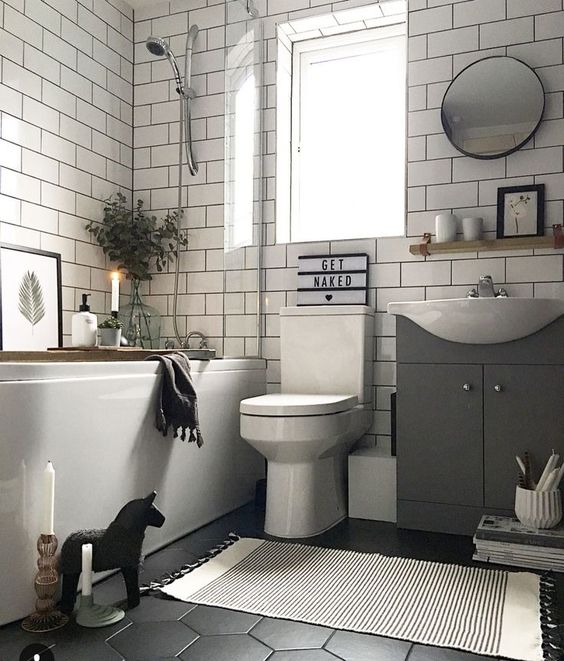 a monochromatic bathroom with a hex tile floor, subway tiles on the walls, a tub, candles and some cute decor