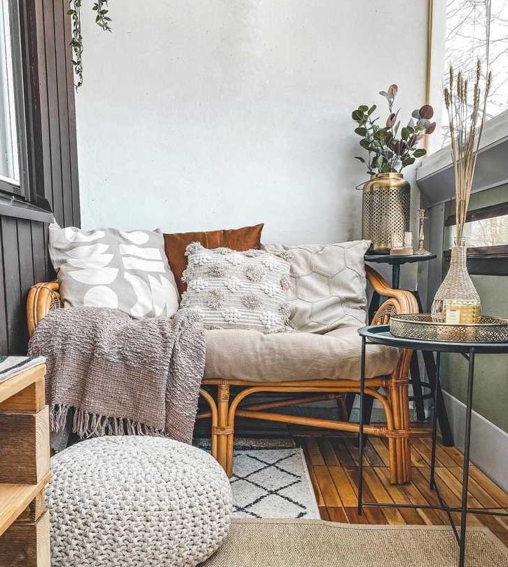 a neutral boho balcony with rattan and wooden furniture, wheat and eucalyptus in a vase, neutral boho textiles and layered rugs is very welcoming