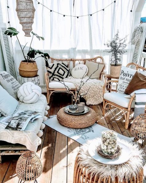 a neutral boho porch with rattan furniture and candle lanterns, lights, potted plants, pillows and textiles