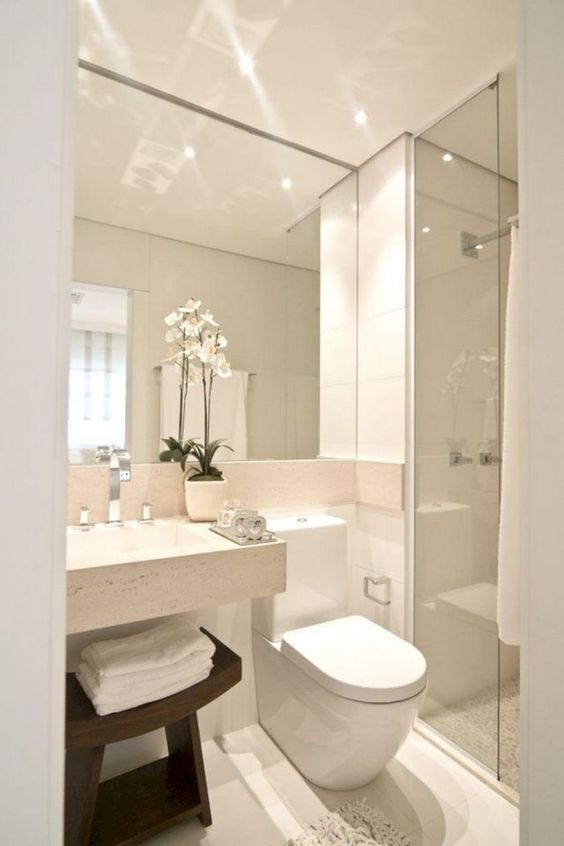 a neutral minimalist bathroom with a large mirror, a square sink, a shower space and a dark stained wooden stool