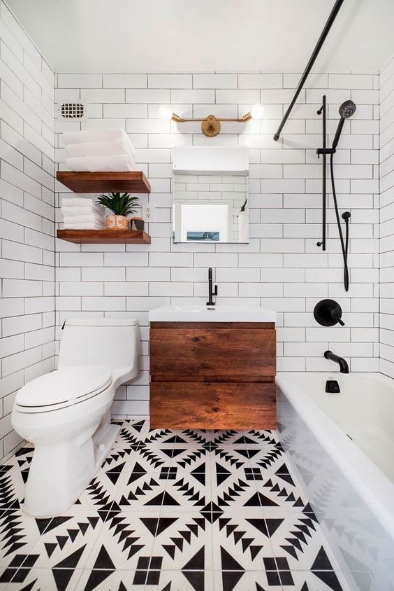 a small and chic modern bathroom with a mosaic floor, a floating wooden vanity, open shelves, a tub and white subway tiles