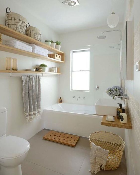 a small and serene bathroom with a tub, open shelves, a sink, wicker and wooden touches here and there