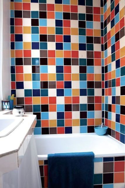a small and very bright bathroom clad with matching tiles of mismatching colors, with a vanity clad with tiles, too and a bold towel