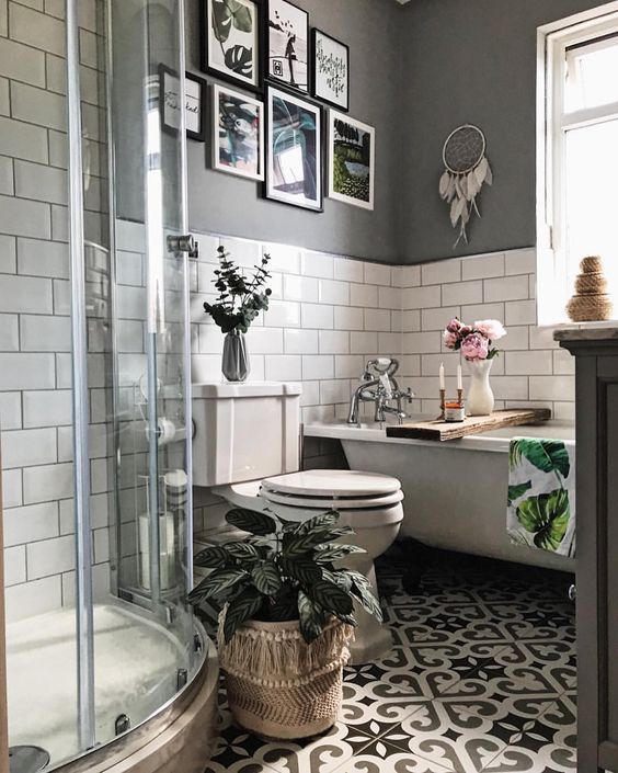 a small boho bathroom with grey and white subway tile walls, a shower space, a gallery wall and potted greenery