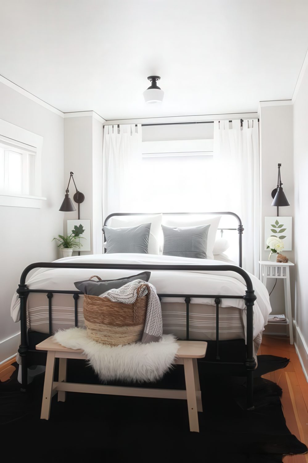 a small chic bedroom with a black forged bed, a black rug, a wooden bench and artworks