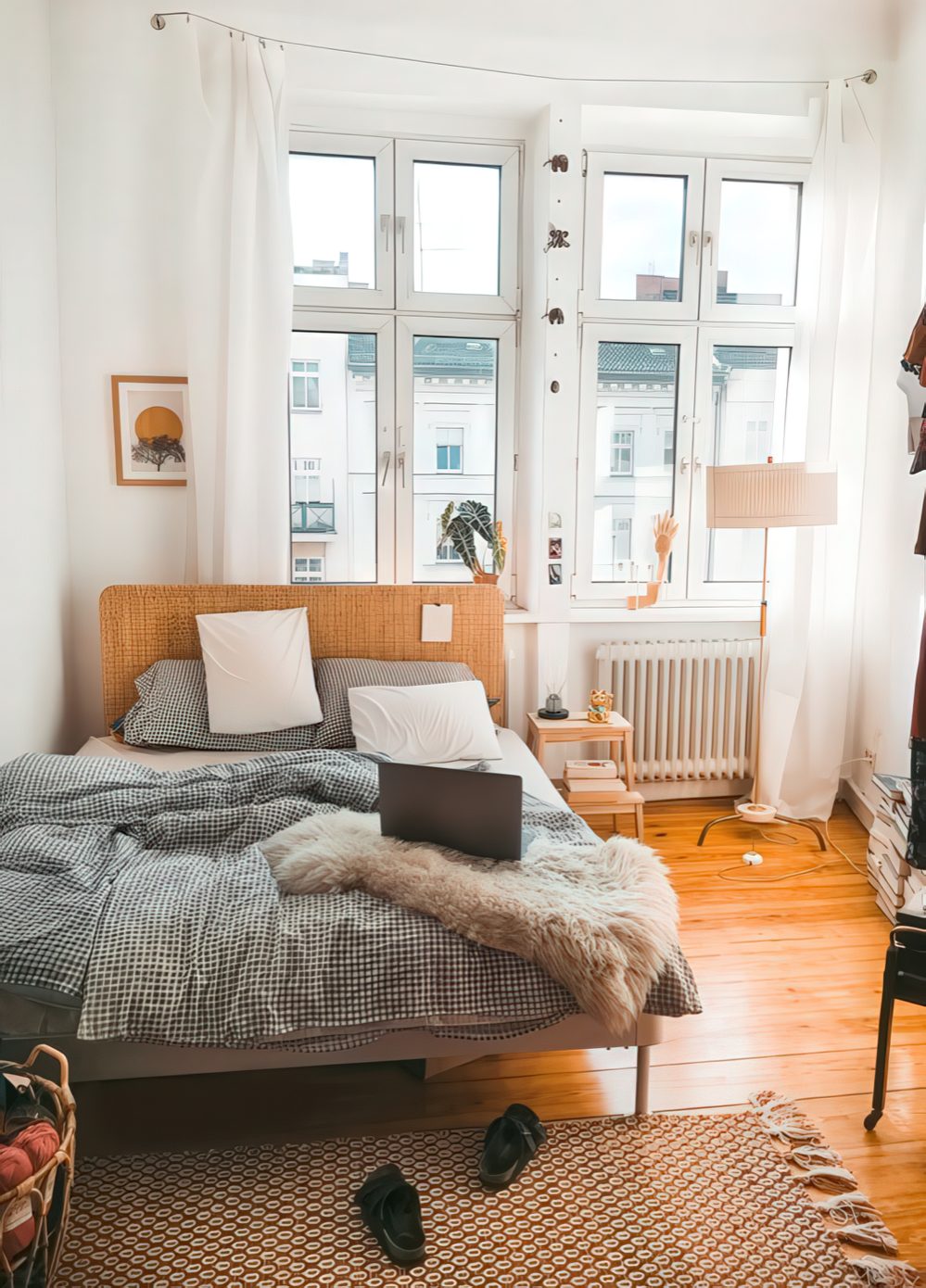 a small modern bedroom with a wicker bed, a floor lamp, catchy printed textiles and a rug plus white curtains