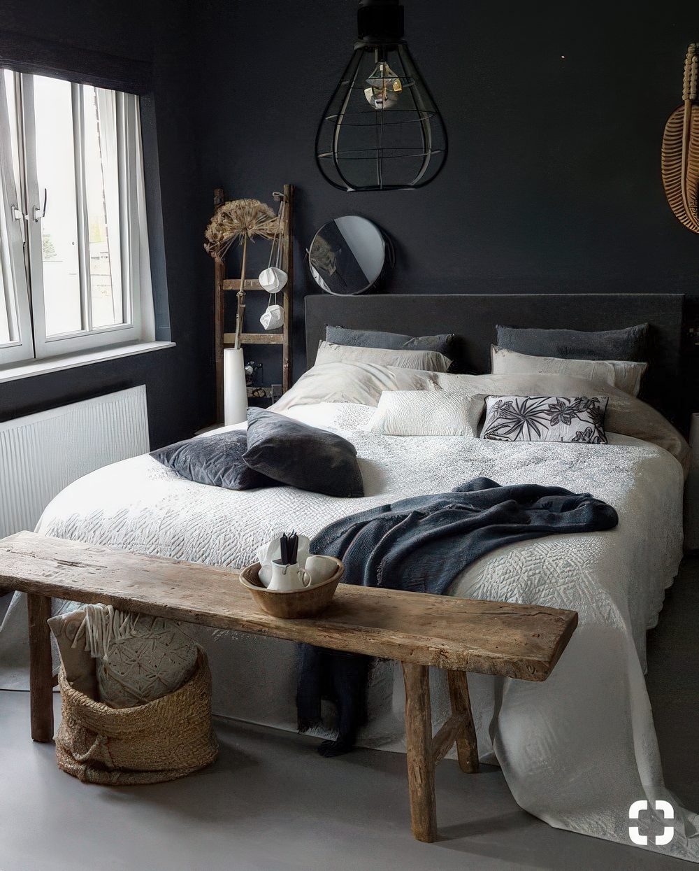 a small moody bedroom with black walls and a bed, with a wooden bench and ladder, pendant lamps