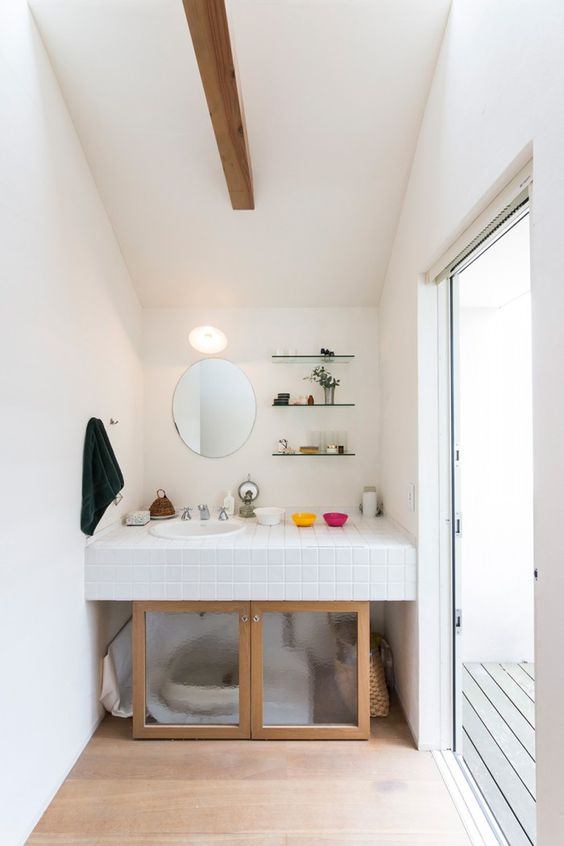 a space under a sink wiht a cat toilet and frosted glass doors plus access to it from both sides