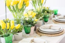 a spring tablescape with bright yellow tulips, fresh greenery and green glasses looks bold, fresh and very spring-like