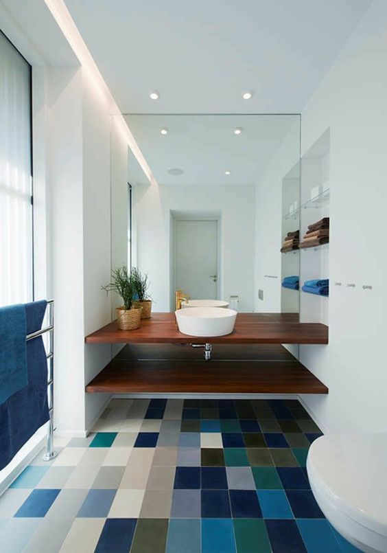 a stylish modern bathroom done in white but with a statement colorful tile floor and matching blue textiles