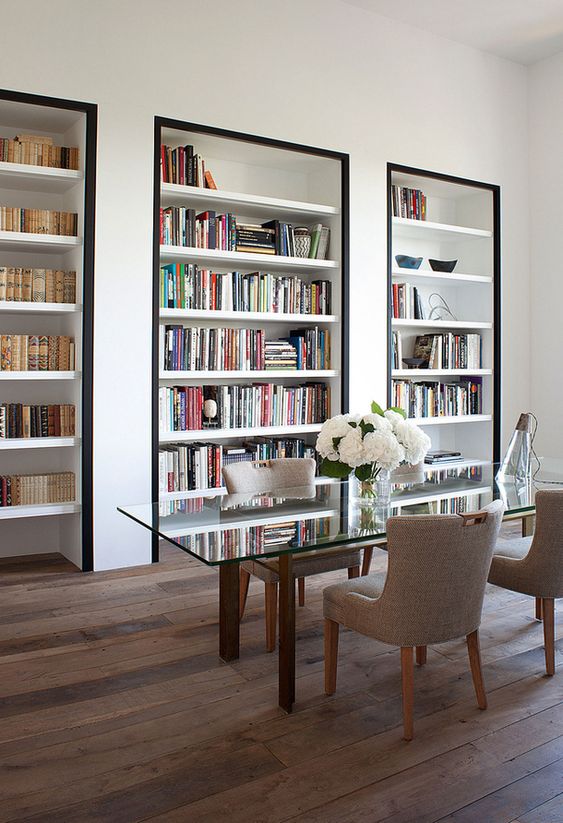 a super refined home office with built-in bookshelves with black framing to accent them as much as possible