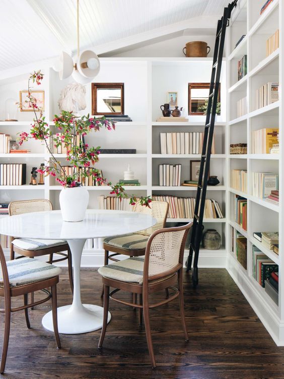 a welcoming mid-century modern dining space with built-in bookshelves, a round table and rattan chairs