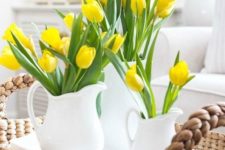 a wicker tray with several matching white jugs and bright yellow tulips for a bold springy look