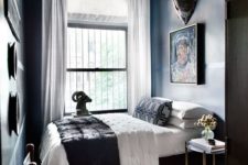 an elegant moody bedroom with dark walls, a catchy chandelier, artworks, an animal rug and leather chairs