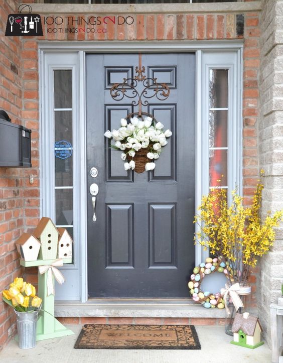 birdhouses on a stand, a bright floral arrangement, a wreath of pastel fake eggs and a basket with white tulips
