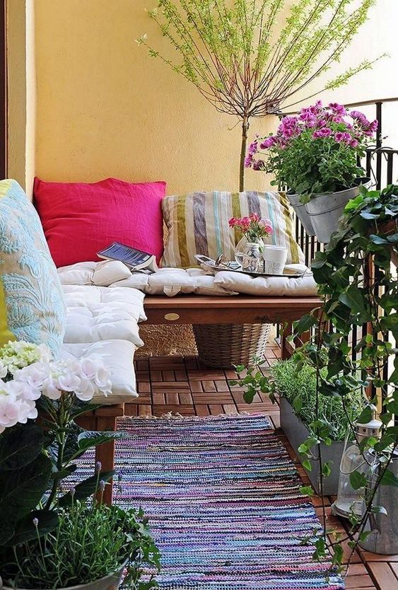 colorful pillows and a boho rug, potted greenery and flowers are bold and cool for a rustic-like balcony