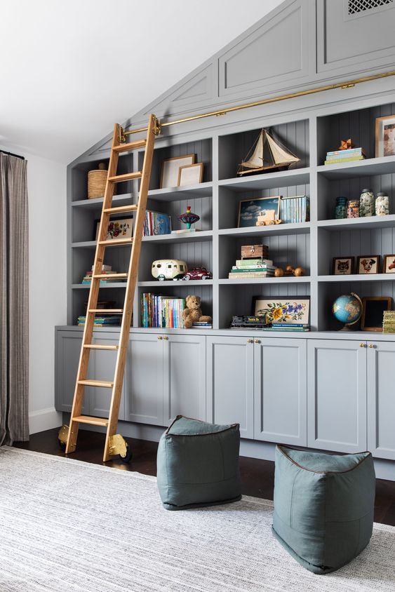 grey built-in bookshelves, blue poufs and a ladder to get all the books comfortably