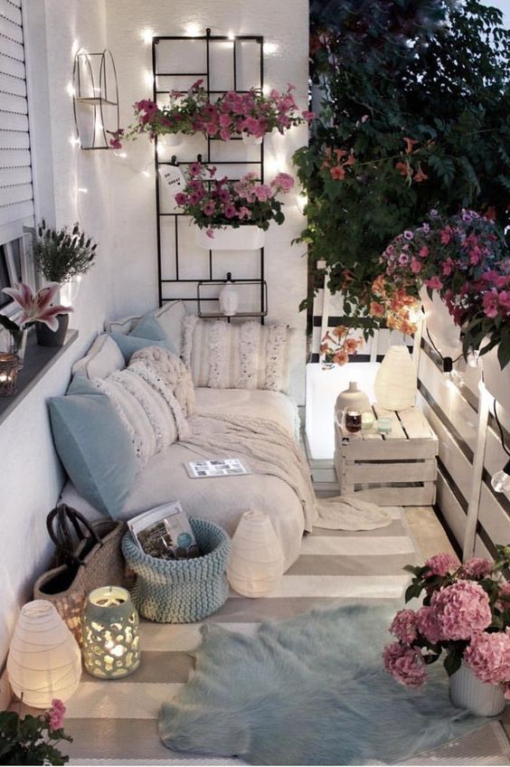 light blue pillows and a basket, potted pink flowers and some lights and lanterns will make your balcony tender and spring-like