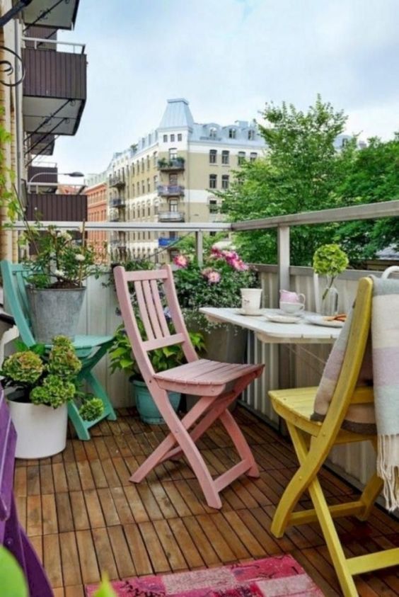 pastel chairs, a colorful rug, potted flowers and greenery for a comfy and chic spring balcony