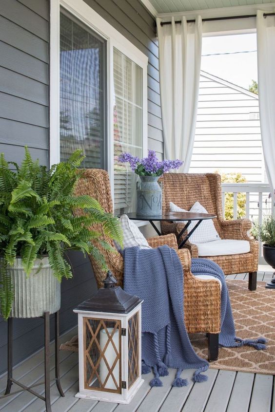potted ferns, purple blooms in a churn, wicker chairs and candle lanterns for a farmhouse spring porch