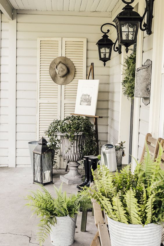 potted greenery and a greenery wreath plus some vintage stuff and lanterns for an elegant spring porch