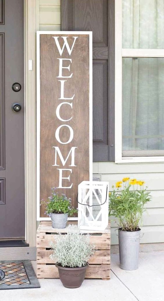 potted greenery and blooms, a candle lantern and a plywood sign for a bright and fun spring porch