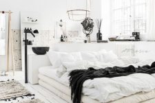 a Nordic bedroom with a bathroom here, with white walls and a whitewashed floor, simple furniture and black touches for drama