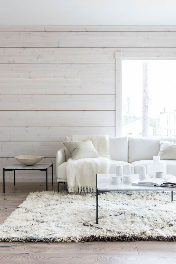 a Nordic living room with whitewashed wooden walls, chic contemporary furniture and lots of candles is welcoming