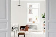 a Scandinavian space with white walls, a whitewashed floor, a white ceiling and leather furniture