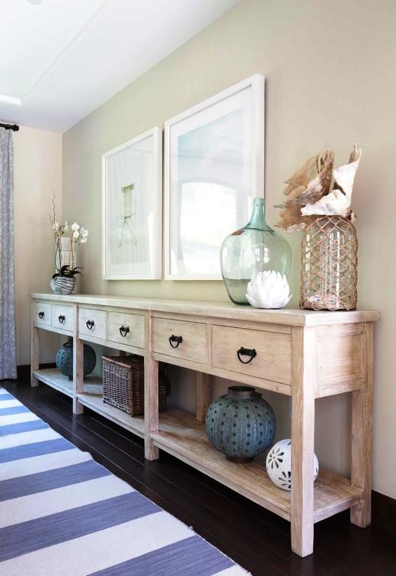 a beautiful and large whitewashed console table with drawers and a long open shelf is great for storage and displaying stuff